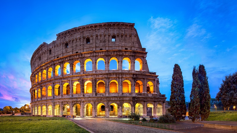 Colosseum i Rom med upplysta f�nsterb�gar och djupbl�tt kv�llsljus.